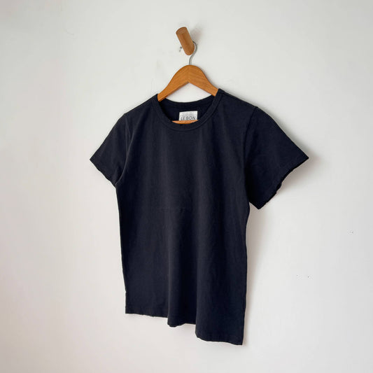 a black cotton shirt with a masculine boxy shape, without the long length. short sleeve and distressed details on the sleeve and bottom edges