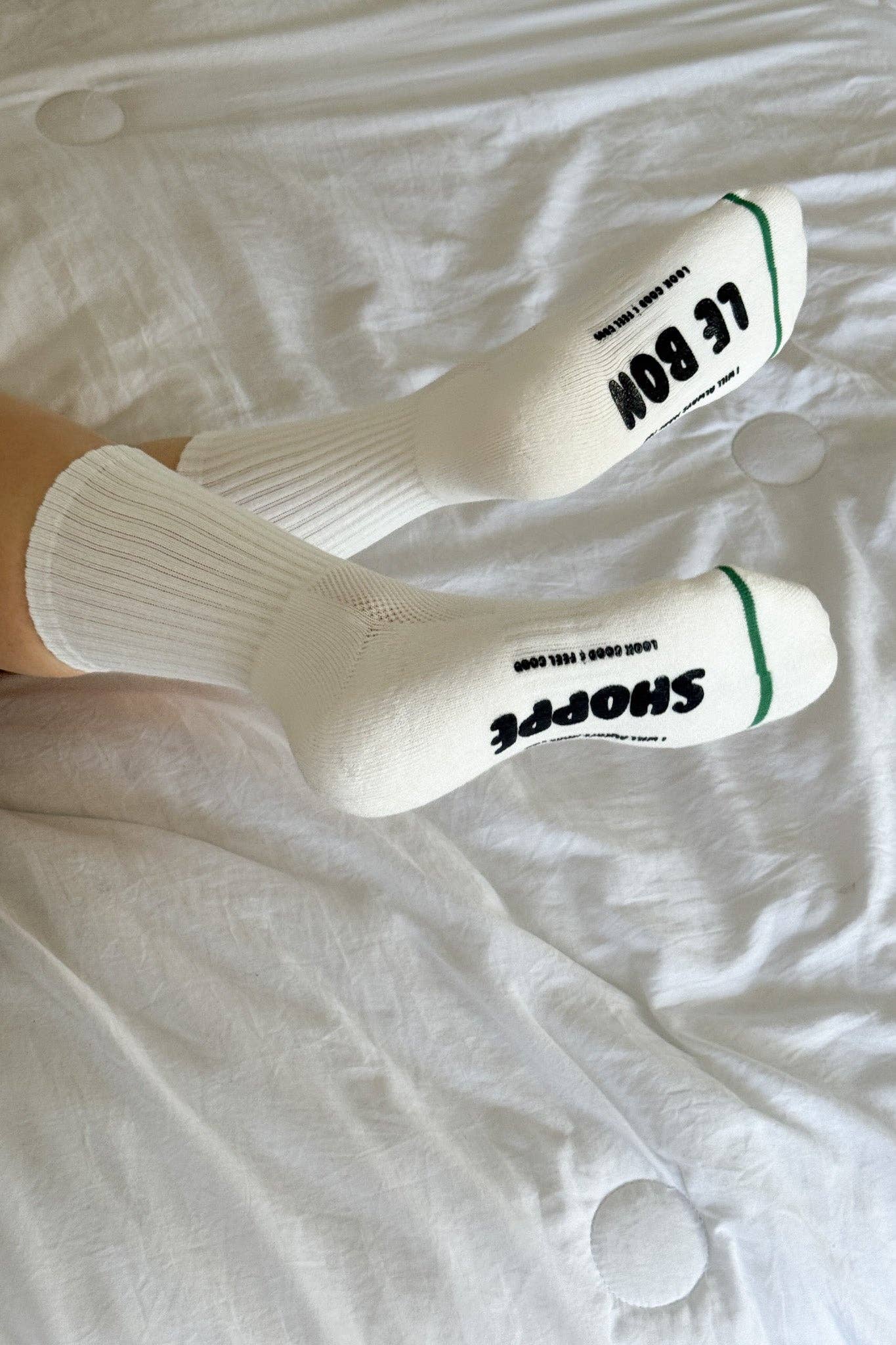 White socks with black text worn on a white bedspread