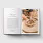 Open book showing a page with text and an image of hands working with clay on a potter's wheel.