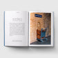 Open book showing text on one page and a photo of a luggage trolley against a brick wall on the other.