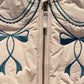 Close-up of a beige jacket with blue embroidery and a visible brand label.
