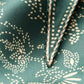 Close-up of green fabric with beige floral pattern and stitching detail