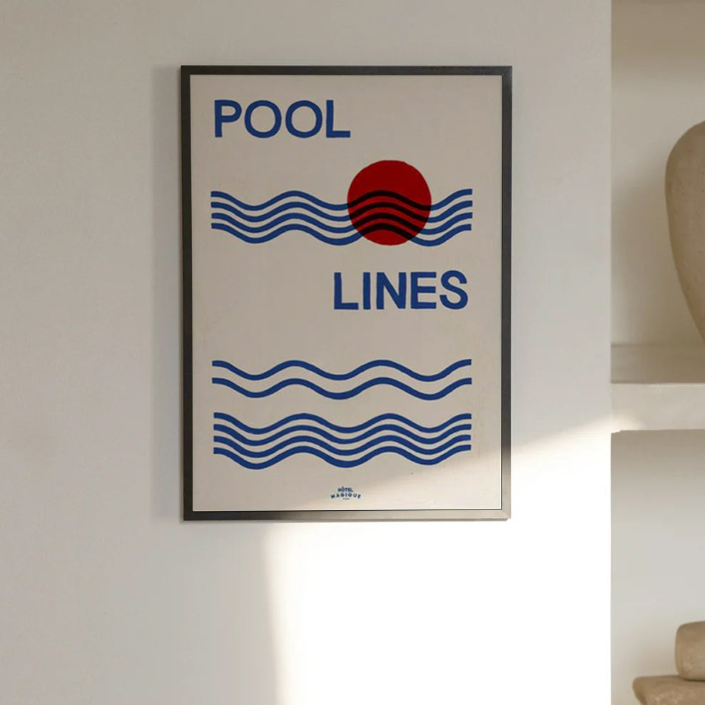 An image depicting Hotel Magique Pool Lines A3 Print. The print has Pool lines written in caps in dark blue, the waves are dark blue as well. The circle is red. The background is white. The print is framed with black border. The frame is hung on a white wall. 