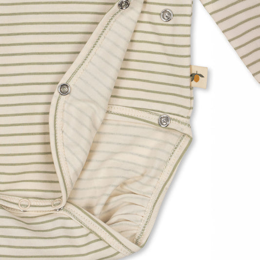 Close-up of a Konges Sløjd long-sleeve newborn bodysuit in soft striped fabric, showing snap button closures at the bottom and side for easy dressing. A small fabric tag with a citrus fruit illustration is visible on the seam.