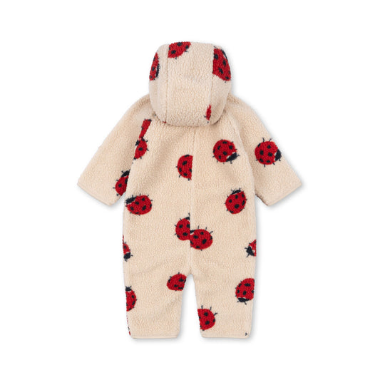 Konges Sløjd Jody Teddy onesie in Ladybug Sand, featuring an all-over red ladybird print on soft cream-coloured sherpa fabric. The hooded design provides extra warmth and comfort.