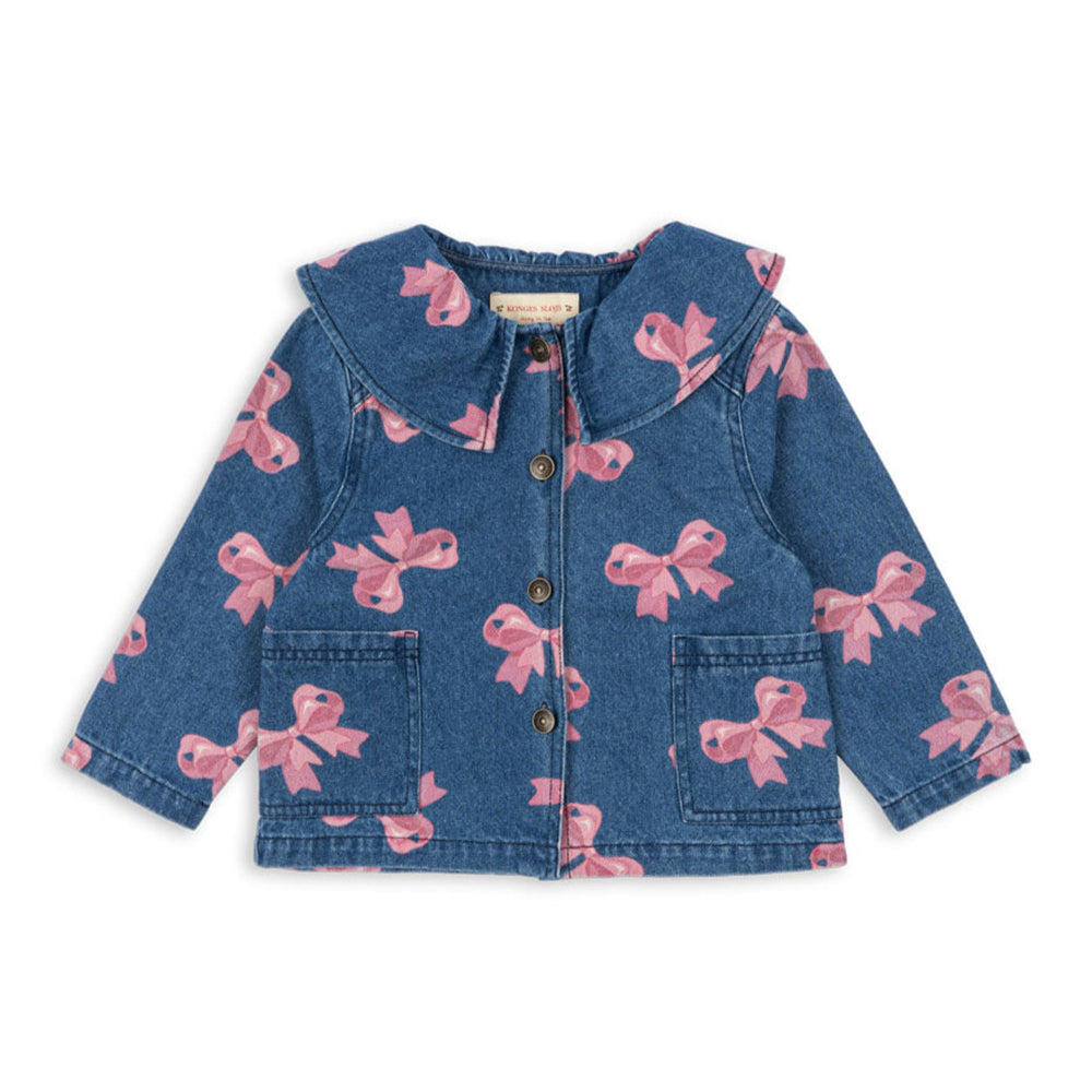 A Konges Sløjd Magot Collar Jacket in Bella Bow print. This charming denim jacket features an all-over pink bow pattern on a classic blue denim base. Designed with a Peter Pan-style collar, front button closure, and two patch pockets, it combines vintage-inspired details with everyday comfort.