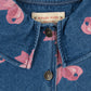 A detailed view of the Konges Sløjd Magot Collar Jacket in Bella Bow print. The image highlights the soft denim fabric, ruffled collar, branded metal buttons, and pink bow pattern.