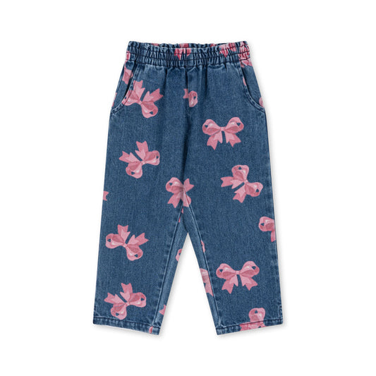 A pair of Konges Sløjd Magot Frill Pants in Bella Bow print. These blue denim trousers feature an all-over pink bow pattern for a playful yet stylish look. Designed with an elasticated waistband for comfort and side pockets for practicality, they offer a relaxed fit perfect for everyday wear.