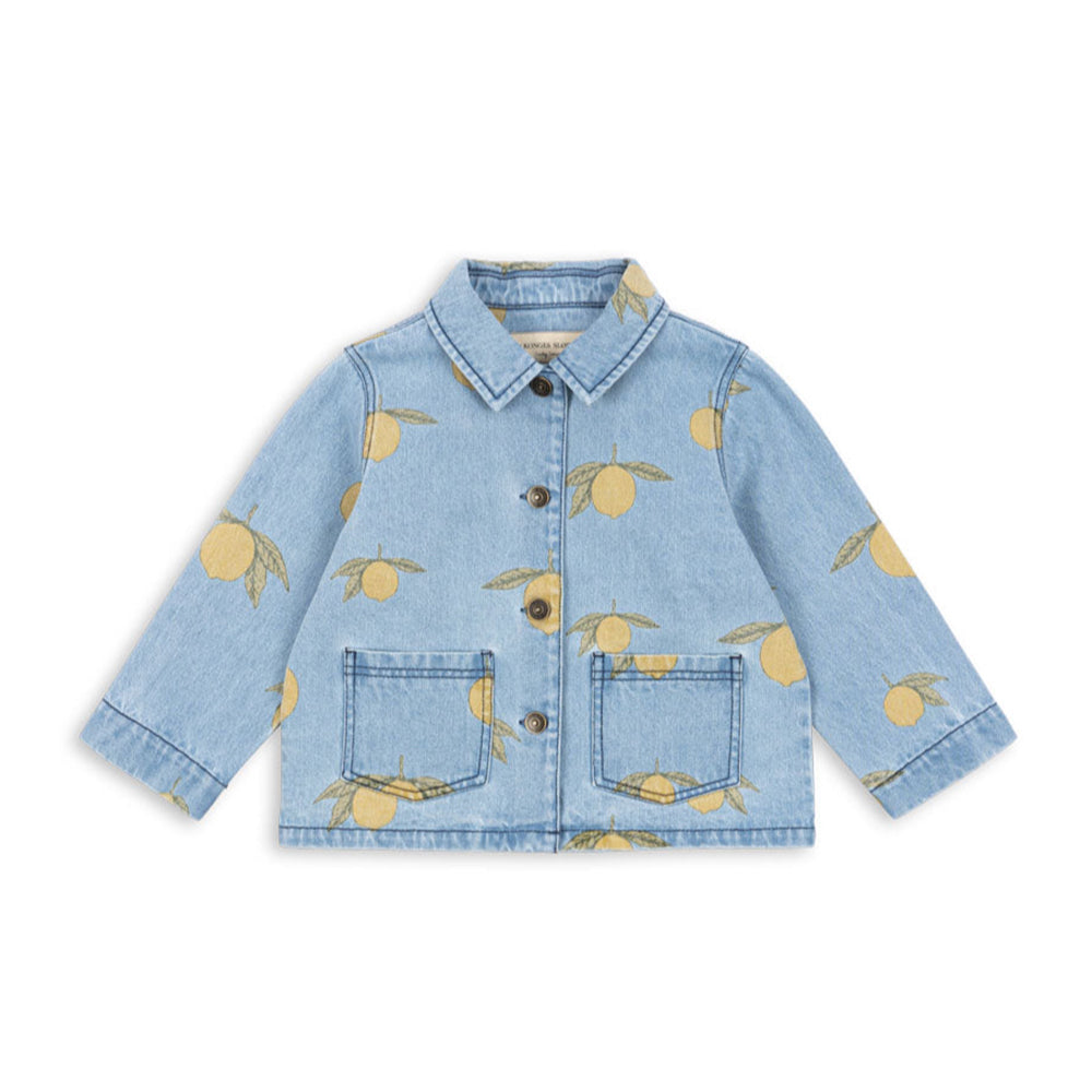 A Konges Sløjd denim jacket featuring an all-over lemon print. This light blue denim jacket is adorned with golden-yellow lemons and green leaves, giving it a playful, vintage-inspired look. Designed with a classic pointed collar, button-down front, and two patch pockets, it offers a timeless yet fun style for little ones.