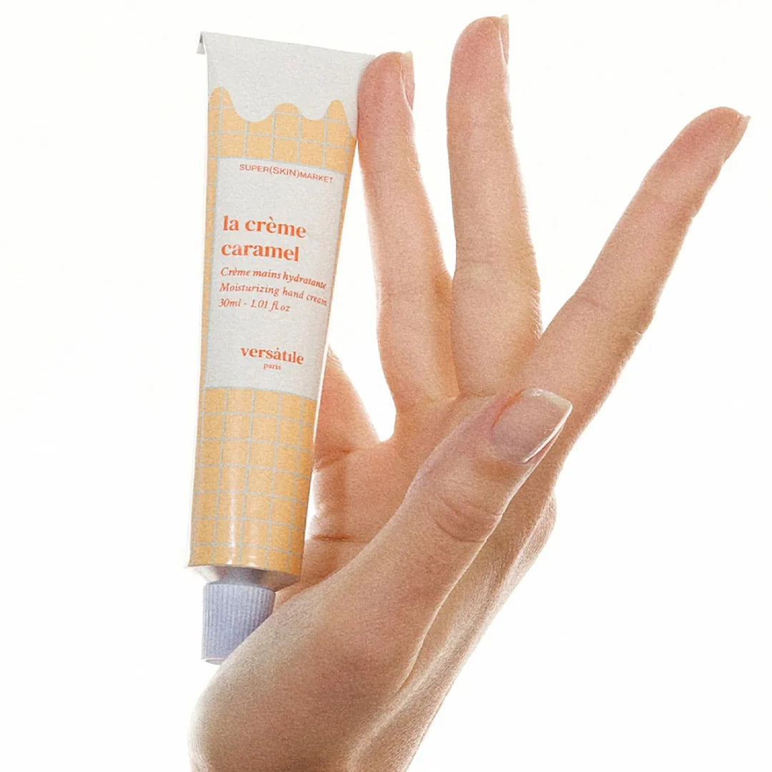 Tube of 'la crème caramel' by versatile with a hand holding it on a white background