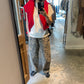 Person taking a mirror selfie wearing Le Bon Shoppe Leopard Arc Pants with a white T-shirt, bright red knit draped over the shoulders, and black trainers inside a modern boutique.