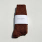 Brown sock with a white label on a light gray background