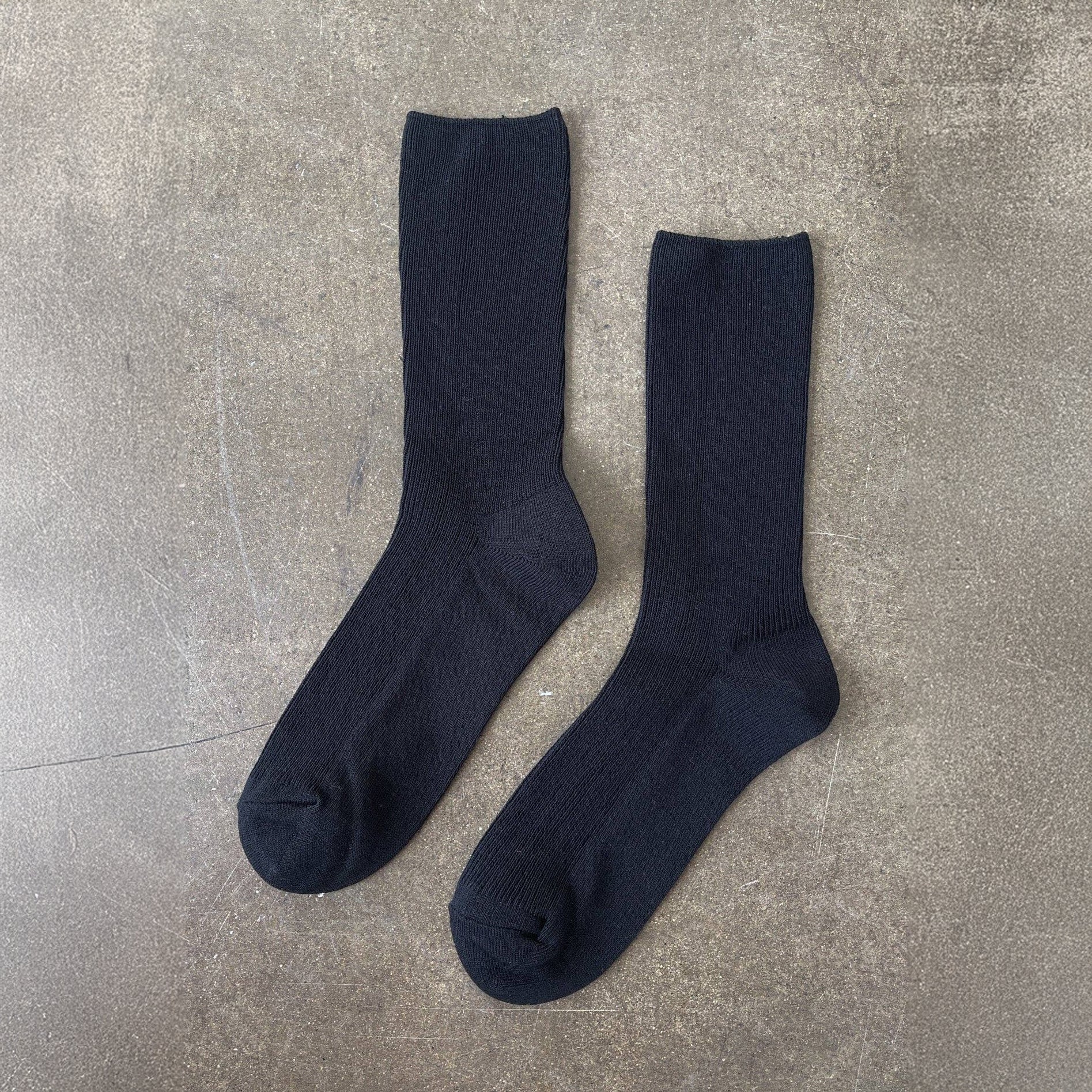 Pair of black socks on a gray concrete surface