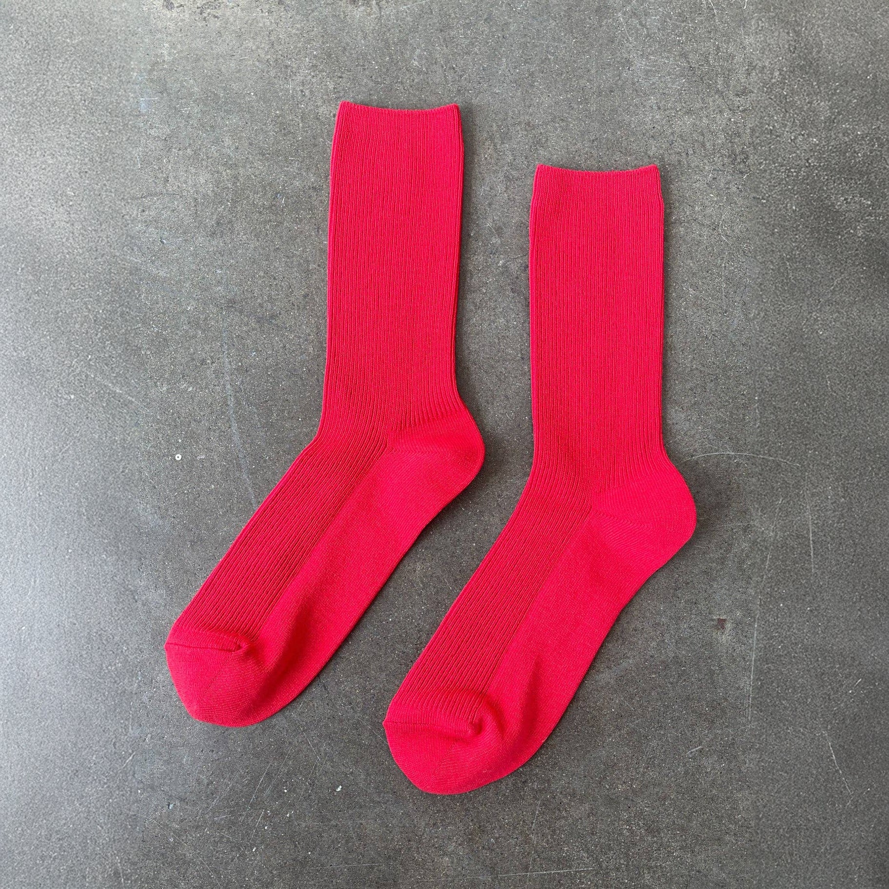 Two red socks on a gray concrete surface