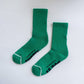 Pair of green socks with white accents on a light gray background