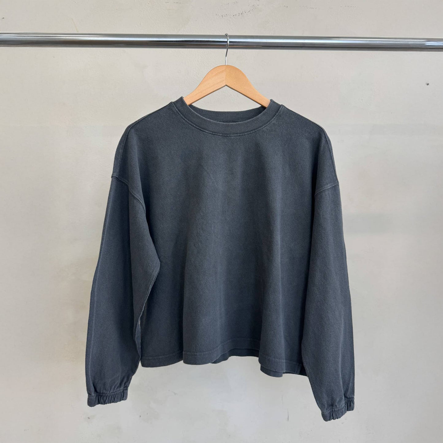 Le Bon Shoppe Naturelle Tee in Coal hanging on a wooden hanger – The tee is displayed on a clothing rail, highlighting its minimal design, soft fabric, and garment-dyed finish.