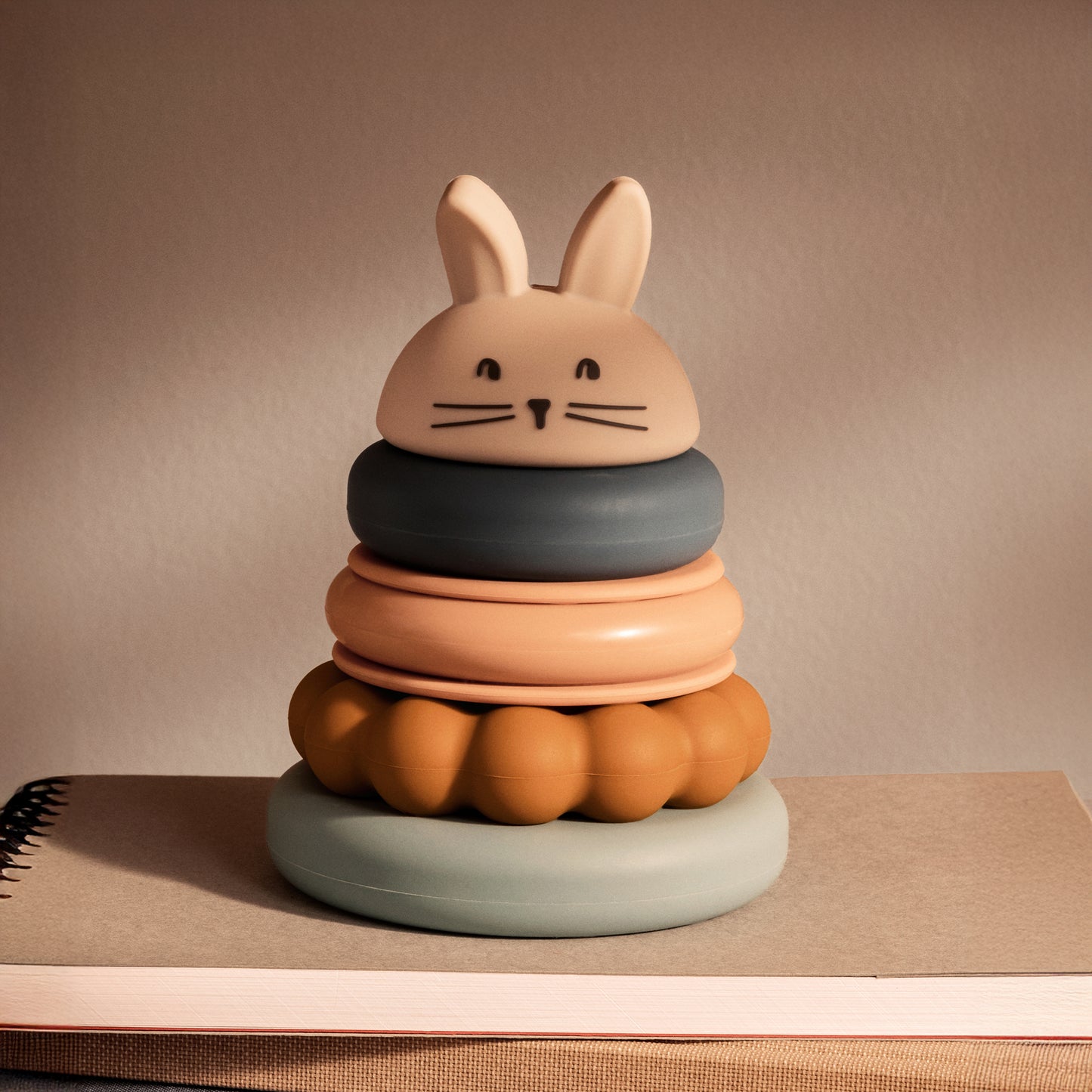 Colourful stacking toy with a rabbit-shaped top on a neutral background