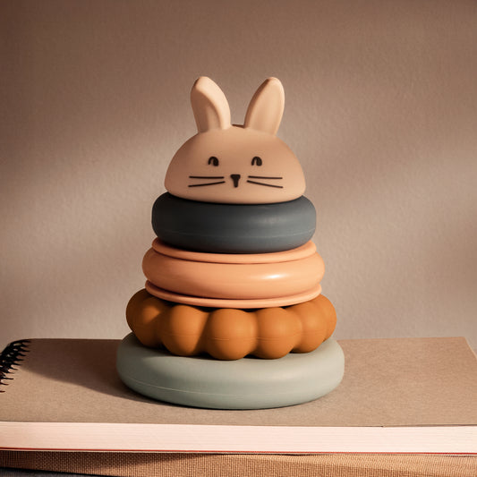 Colourful stacking toy with a rabbit-shaped top on a neutral background