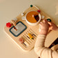 Child playing with a wooden kitchen toy set on a beige table