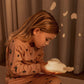 Child holding a night light in a warm, cozy setting