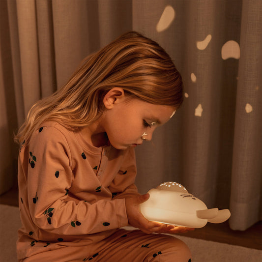 Child holding a night light in a warm, cozy setting
