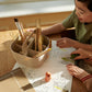Child engaged in art or craft activity with materials on a table.