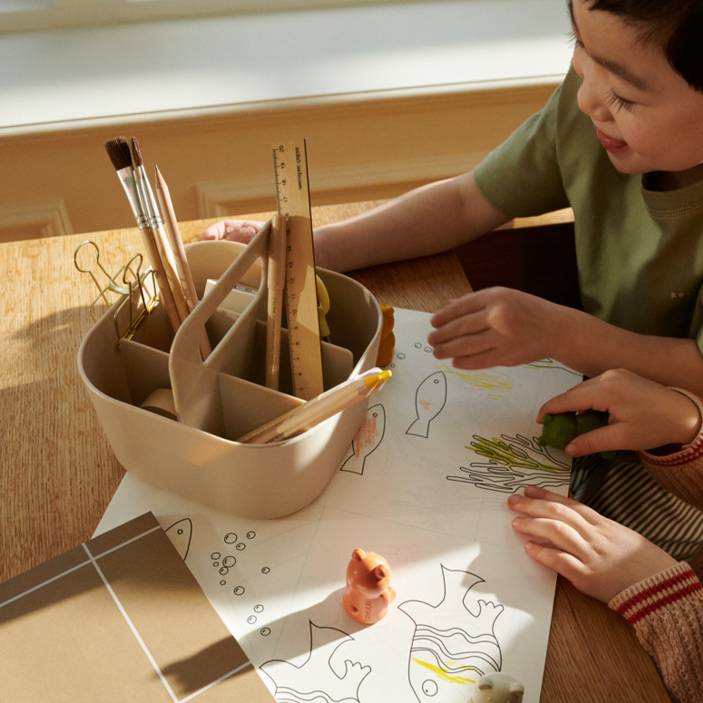 Child engaged in art or craft activity with materials on a table.