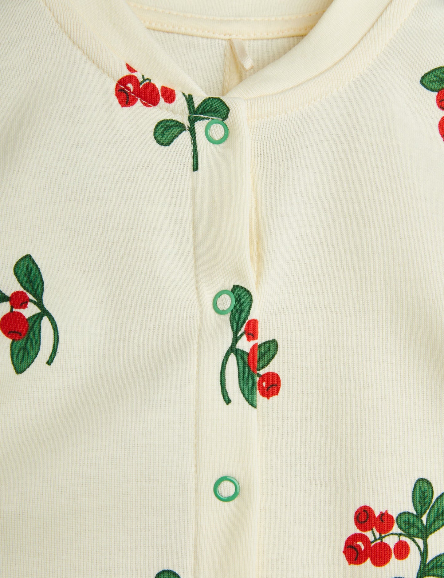 A detailed close-up of the snap button closure and berry print, highlighting the soft organic cotton fabric and vibrant colours.