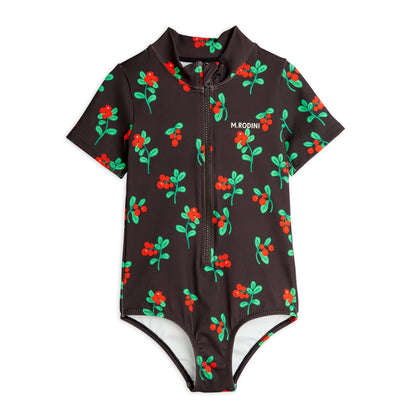 A short-sleeved children's swimsuit in deep brown, featuring an all-over red berry print with green leaves. Designed with a high neck, front zip closure, and a small "M. Rodini" logo on the chest.