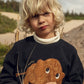 Child wearing a black sweater with a mammoth design outdoors