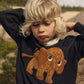 Child wearing a black sweatshirt with a brown mammoth design outdoors