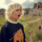Child wearing a black sweater with an elephant design in a natural setting
