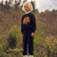 Child wearing a black sweater with a mammoth design in a natural setting