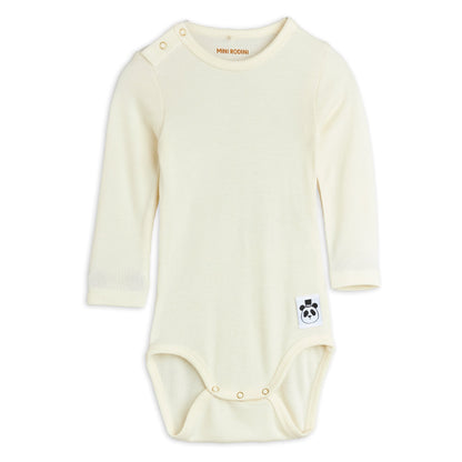 Cream-coloured baby onesie with a small logo on a white background