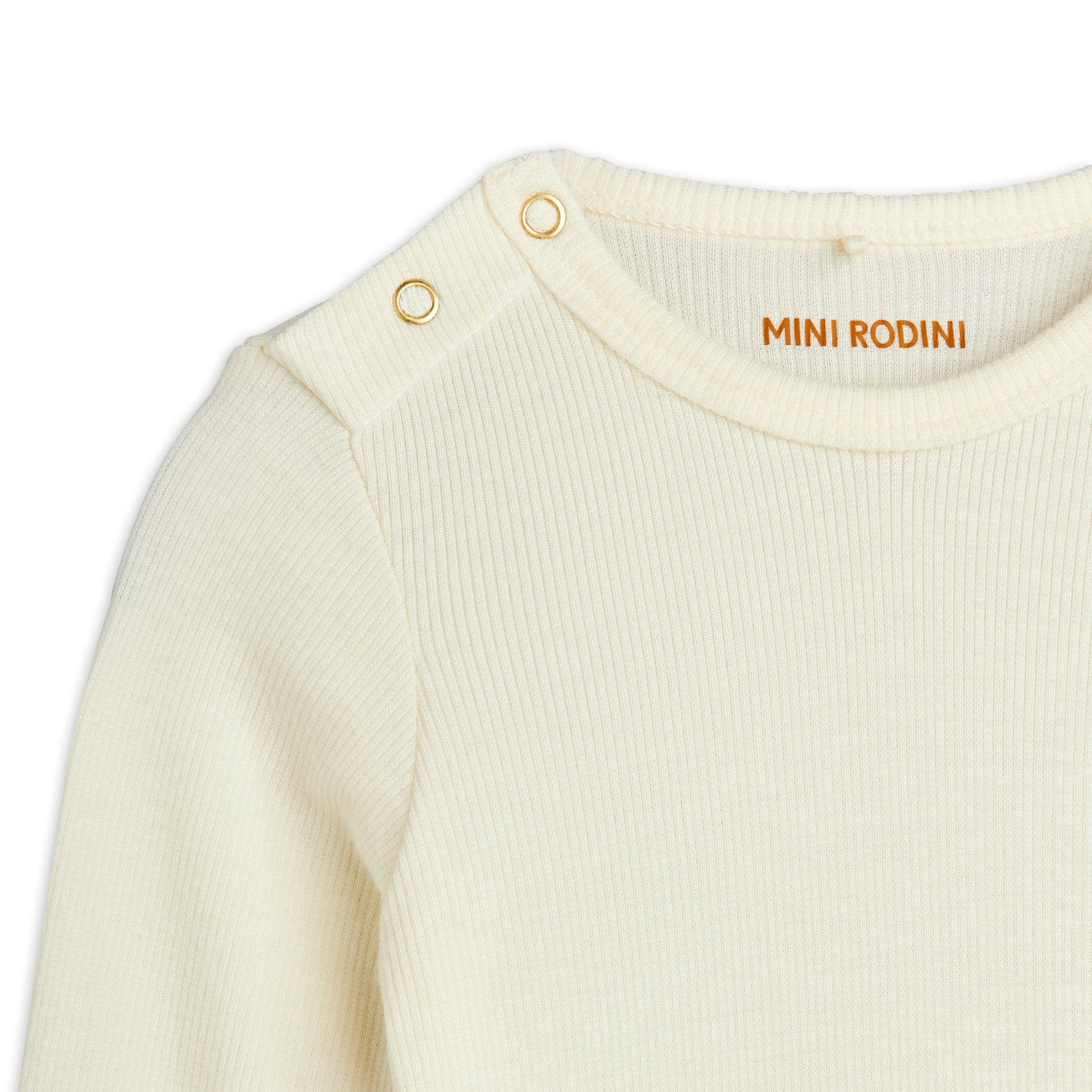 Close-up of a cream-coloured baby outfit with 'Mini Rodini' branding on a white background
