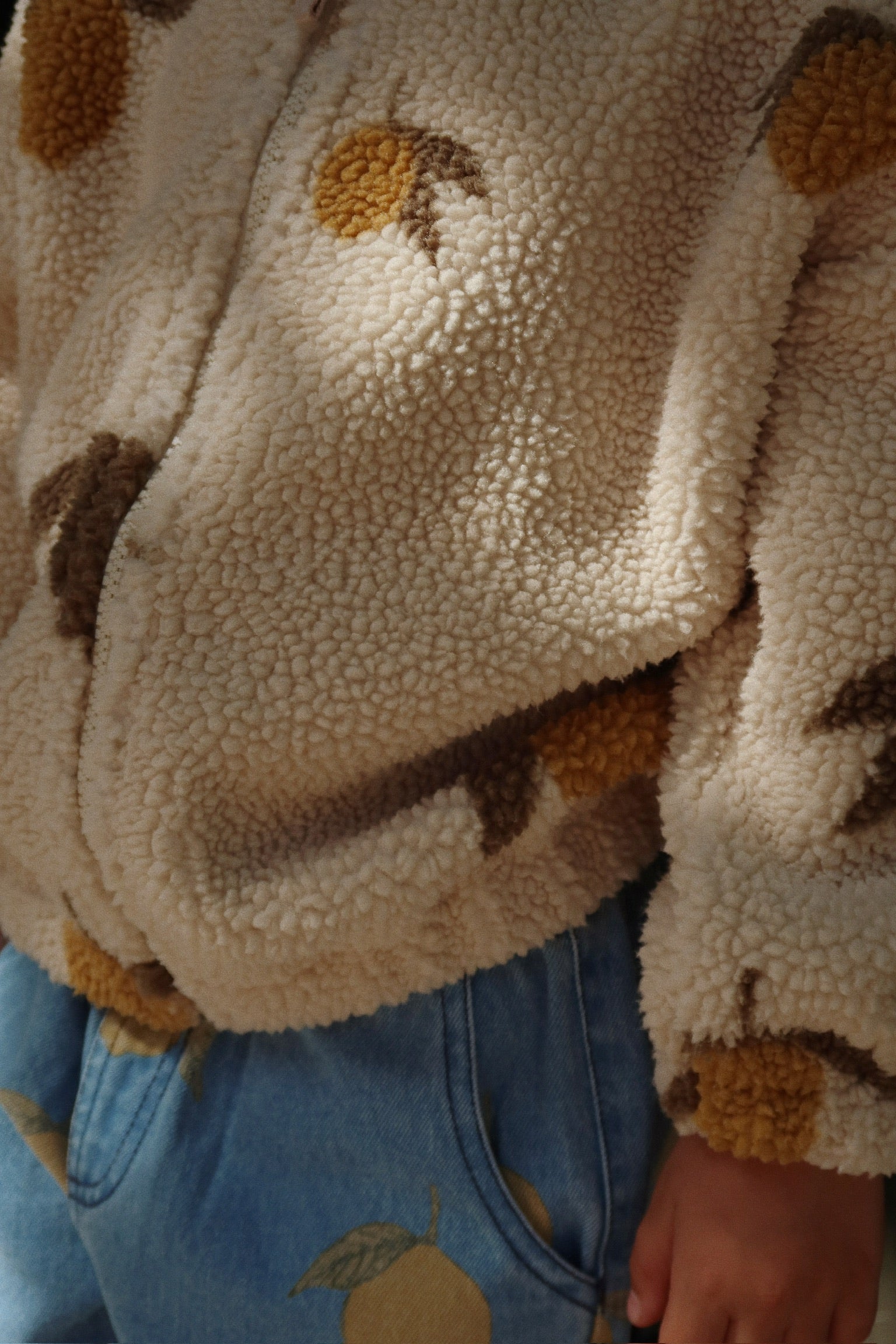 Close-up of Konges Sløjd Magot Pants in Lemon Denim and Jody Teddy Jacket – A cosy-textured teddy fleece meets soft blue denim adorned with delicate lemon prints. Thoughtfully designed for little explorers who love comfort with a touch of playful charm.