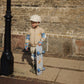 Child holding a skateboard against a brick wall
