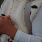 Close-up of a person wearing a white sweater with a patterned vest over it.
