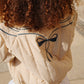 Beige puffer jacket with a black bow detail on a neutral background
