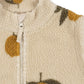 Close-up of a textured fabric with orange and leaf patterns on a beige background