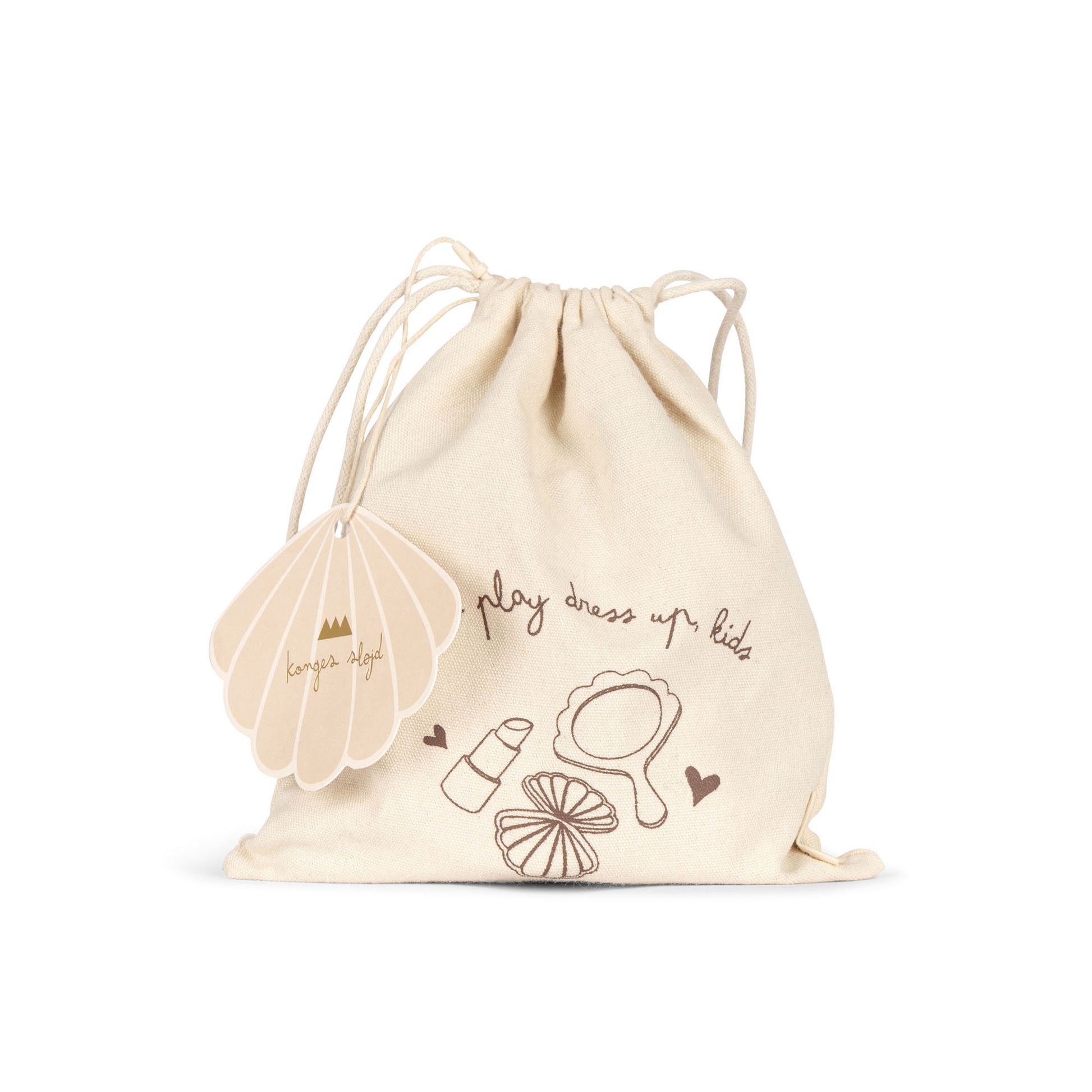 A cream-coloured cotton drawstring bag with brown illustrations of a mirror, lipstick, and other makeup items. The bag features the handwritten-style text "play dress up kids" and has a scalloped shell-shaped tag with the Konges Sløjd logo.
