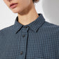 Close-up of the front collar and button details of the oversized blue checkered shirt. The black buttons contrast with the blue grid pattern, and the fabric has a soft, slightly textured feel.