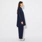 Side view of the model wearing the oversized navy cotton shirt, revealing its long and relaxed fit. The curved hem falls just below the hips, emphasizing the flowy nature of the lightweight fabric.