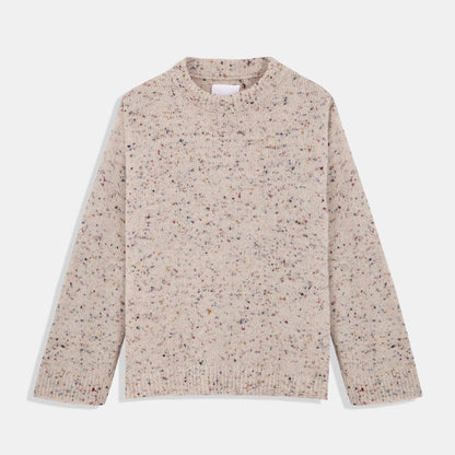 A standalone image of the cream-coloured speckled knit sweater laid flat on a white background. The round neckline, long sleeves, ribbed cuffs, and hem are visible, highlighting the texture and multicoloured flecks in the fabric.