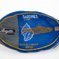 A single oval-shaped wrapped food product on a plain white background. The package is predominantly blue with gold/yellow border lines, white text reading 'SARDINES & LINGUES' and 'BOITE DE CASSERVE 100gr', a fish illustration, and a black oval label on the left that says 'Brigitte FINANCIA'.