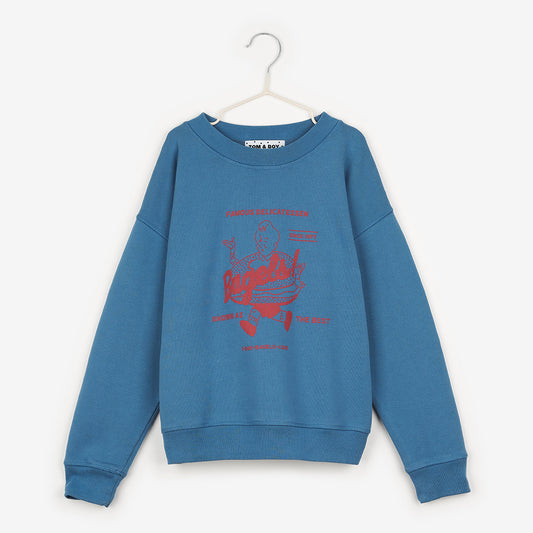 A mid blue sweatshirt  featuring a vintage diner-style red logo, depicting a boy running along with a giant bagel around his waist. It says "famous delicatessen... Bagels!" at the top of the logo and "known as the best" at the bottom, and also "since 1897"