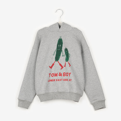 A grey hoodie with two green pickles smiling, holding hands and walking with red boots on. Below the cartoon pickles it says Tom & Boy in red and below that it says Lower East Side, NY. 