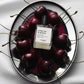 Versace perfume bottle surrounded by cherries on a reflective surface