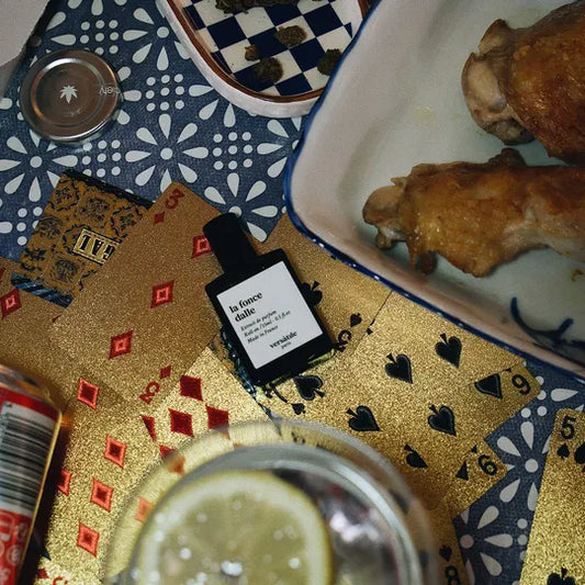 Playing cards with a bottle of La Foncee on a table with food and drinks.