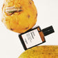 Perfume bottle labeled 'accro discorde' next to a pineapple on a white background